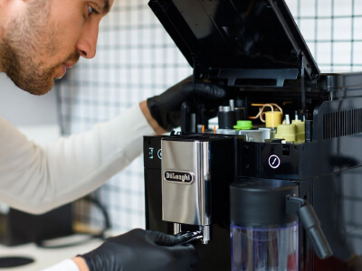 Мастер проводит чистку кофемашины DeLonghi от накипи